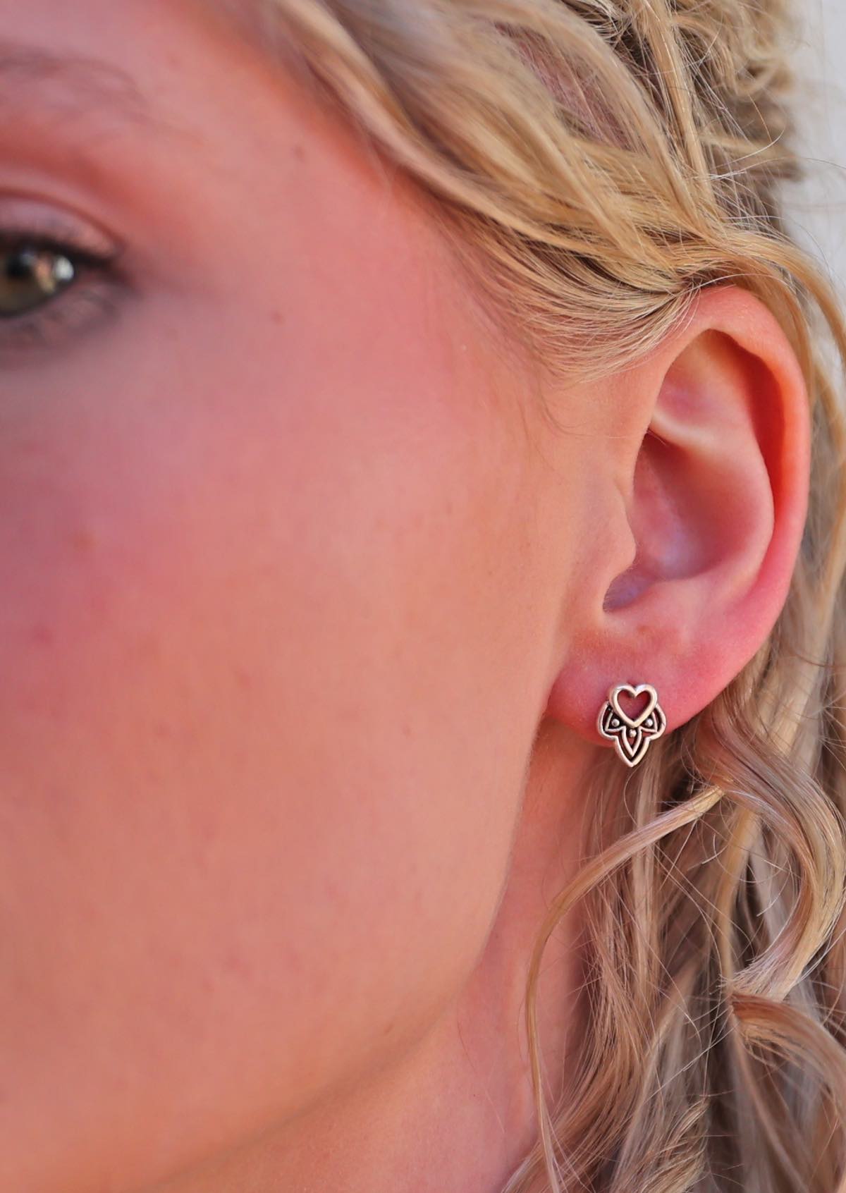 woman wearing sterling silver boho heart stud earrings featuring a tribal-inspired shape within a heart outline
