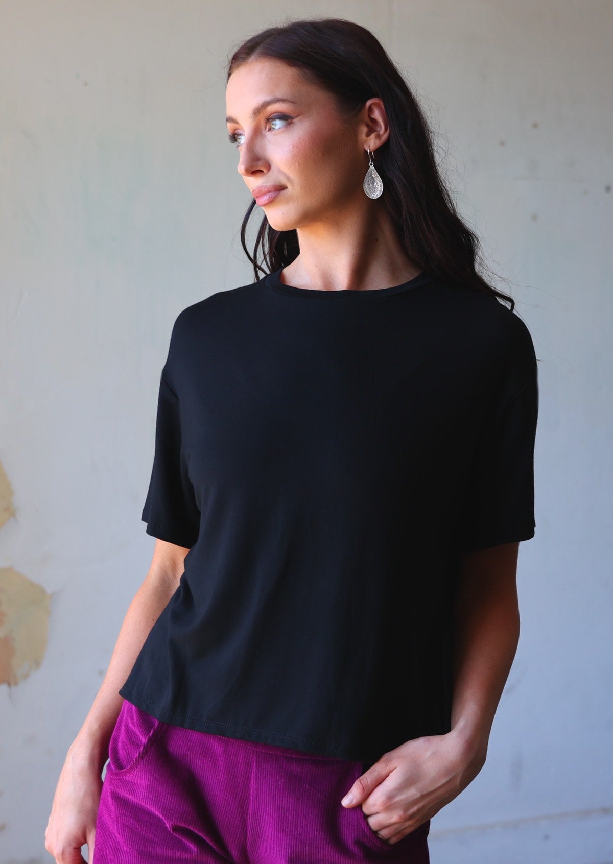 woman in loose fit black t-shirt over purple corduroy pants