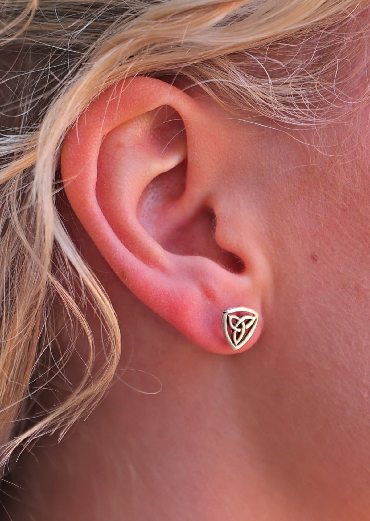 close up of woman wearing sterling silver Celtic Triangle stud earring background.