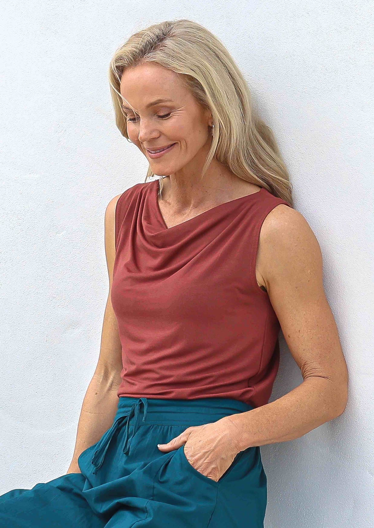 Woman wearing a terracotta coloured singlet top paired with teal pants
