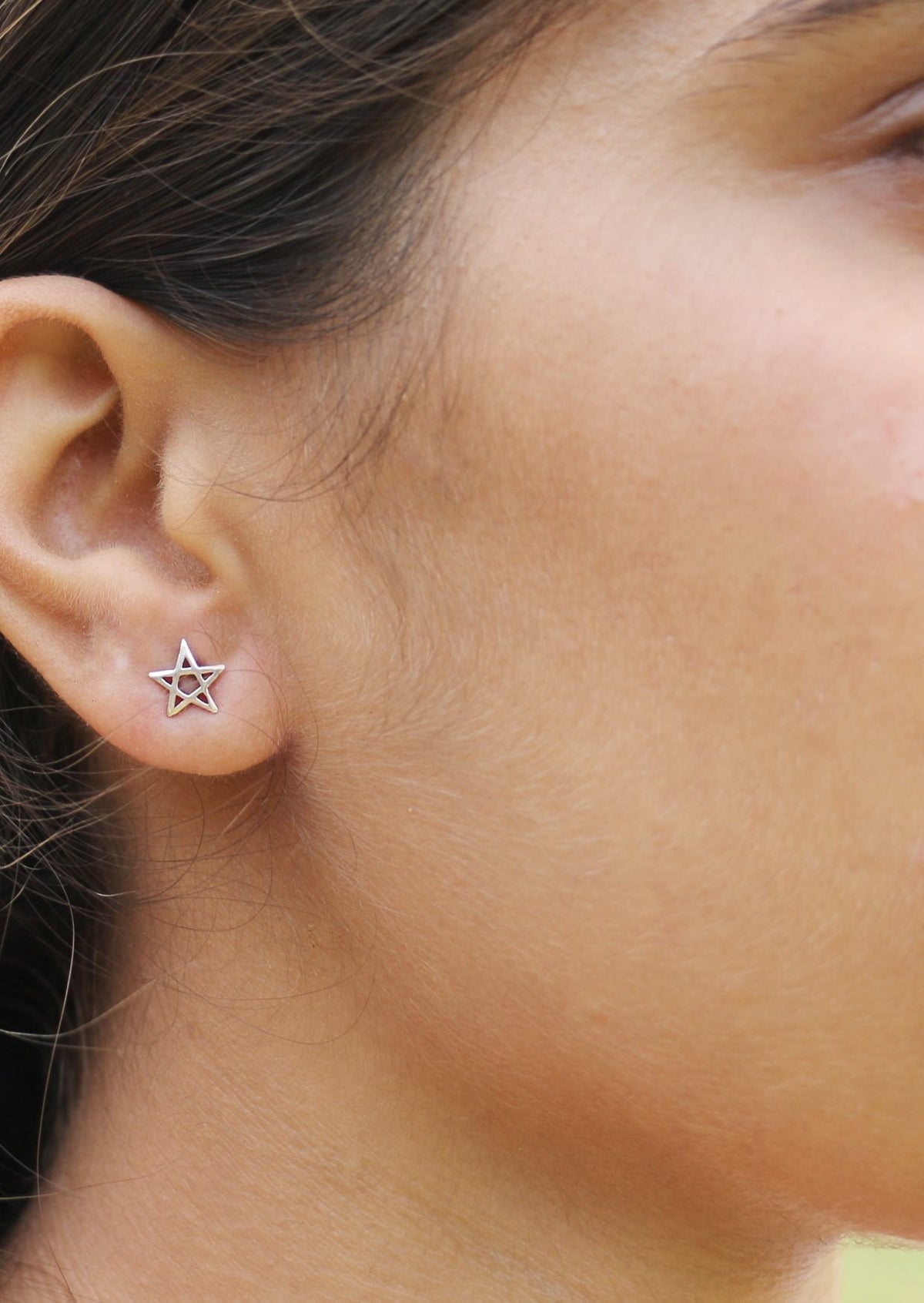 Close-up of an ear wearing a sterling silver star shaped studs with butterfly backs