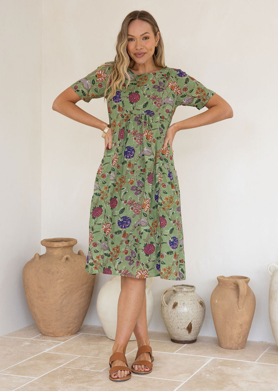 Woman wearing a green based floral print, 100% cotton dress.