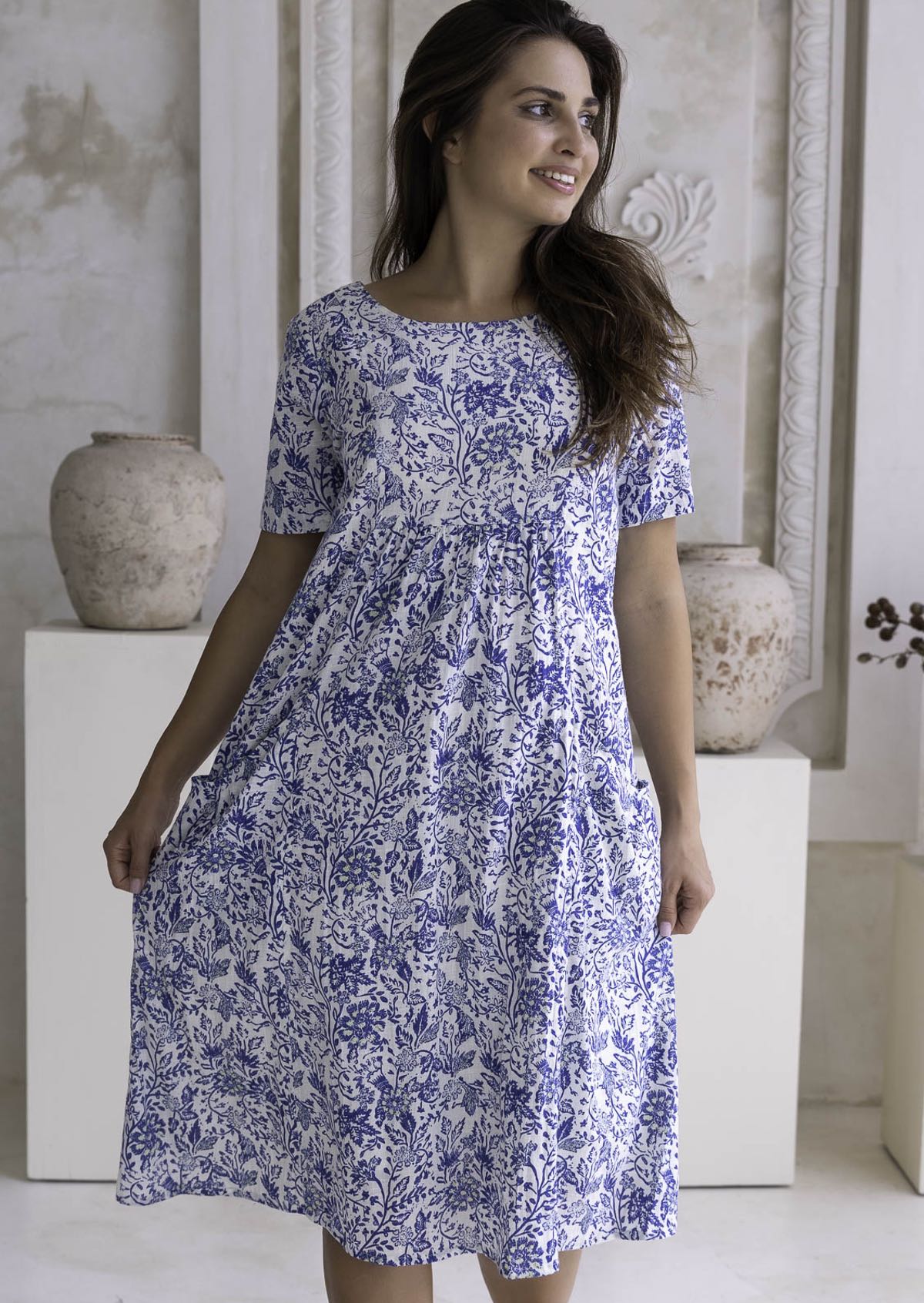 Woman wearing a blue floral cotton dress, 100% cotton, knee length, relaxed fit.