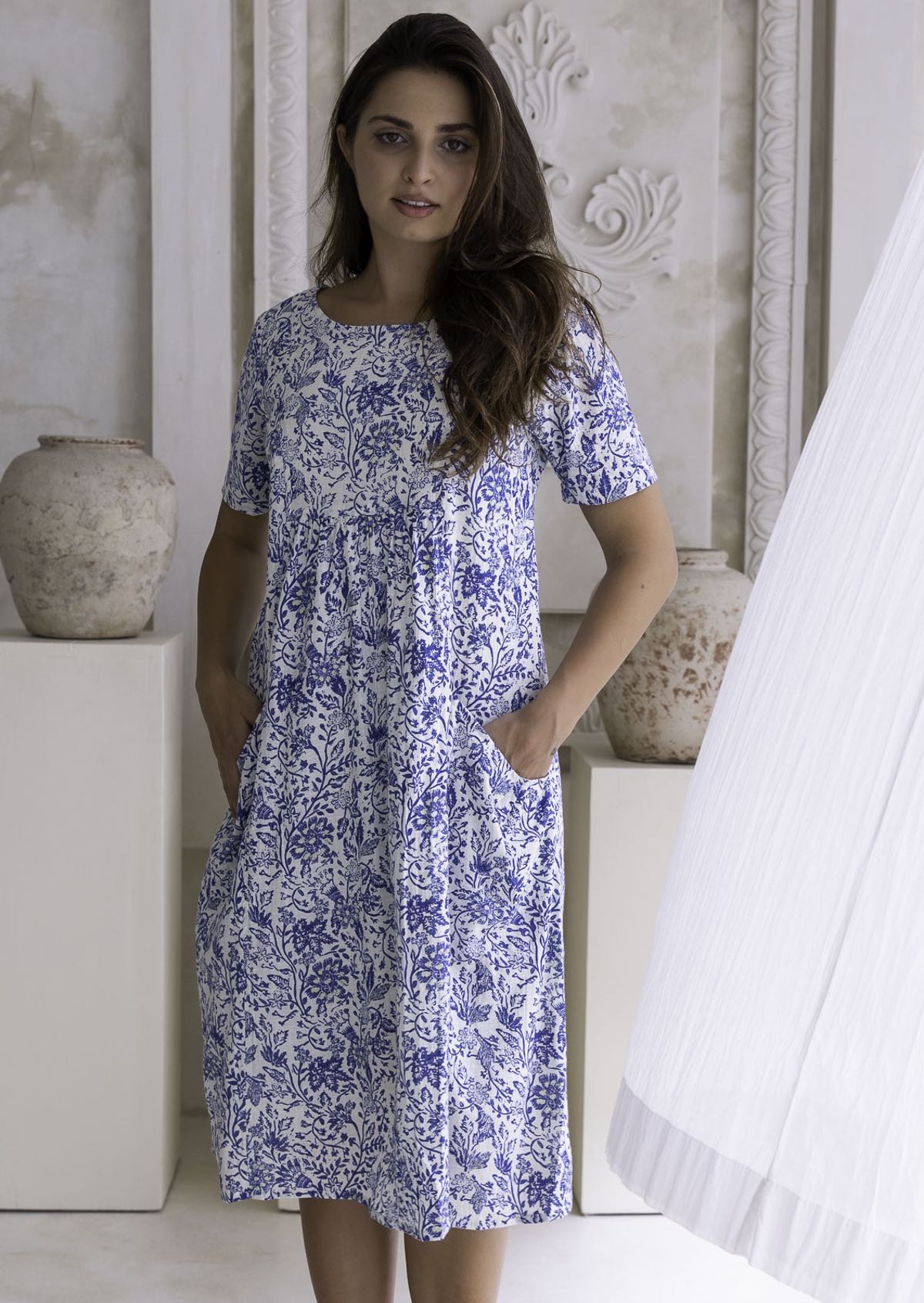 Woman wearing a blue floral cotton dress with her hand in pocket.