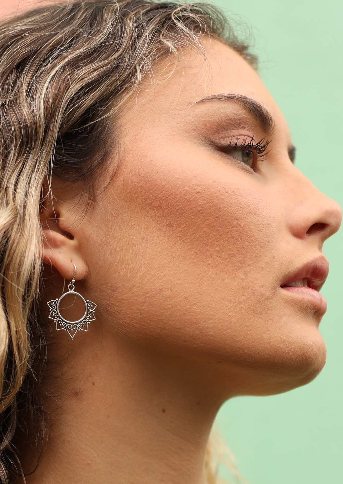 Woman wearing dangly silver earring with boho design