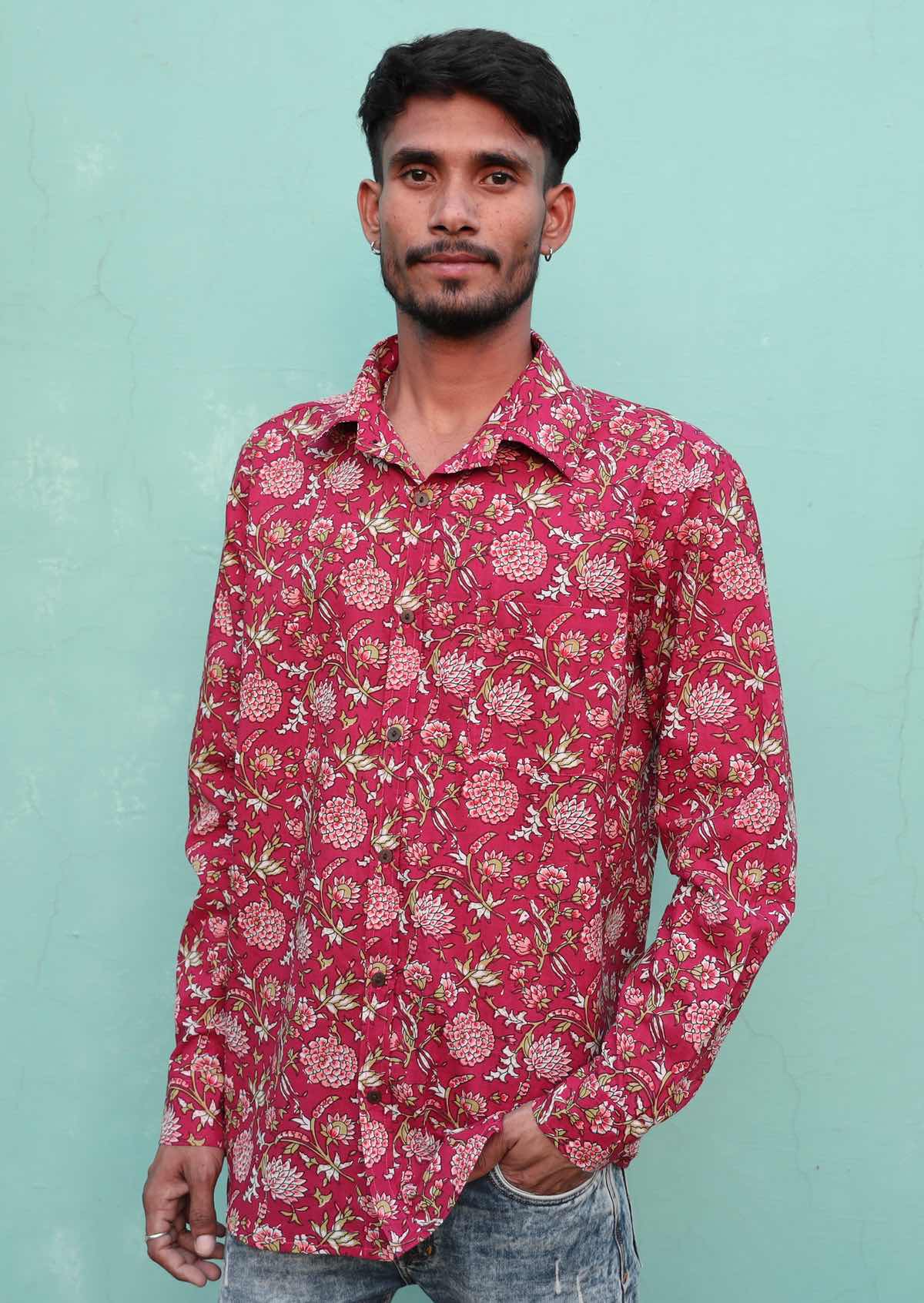 Man poses in long sleeve cotton button through shirt, in cranberry based floral print