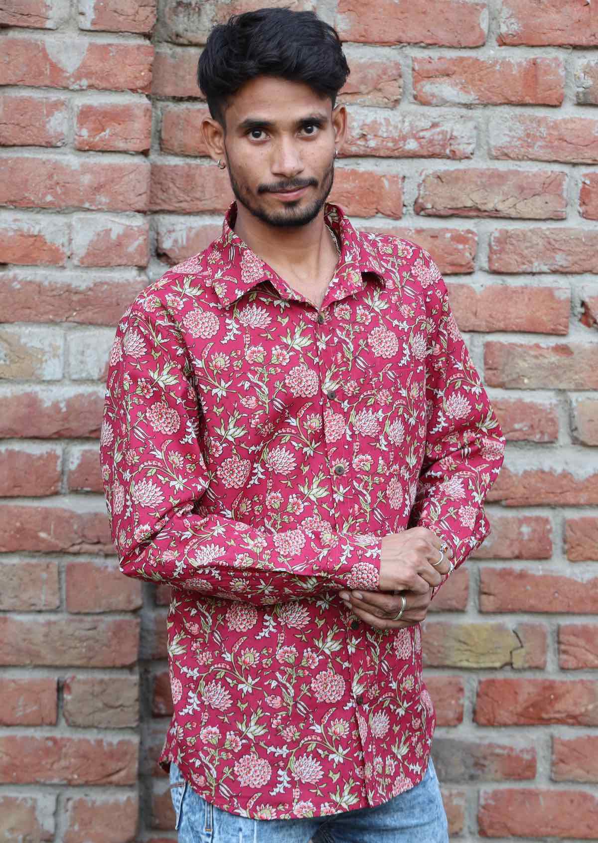 Man poses in long sleeve cotton button through shirt, adjusting the button on the cuff of one sleeve