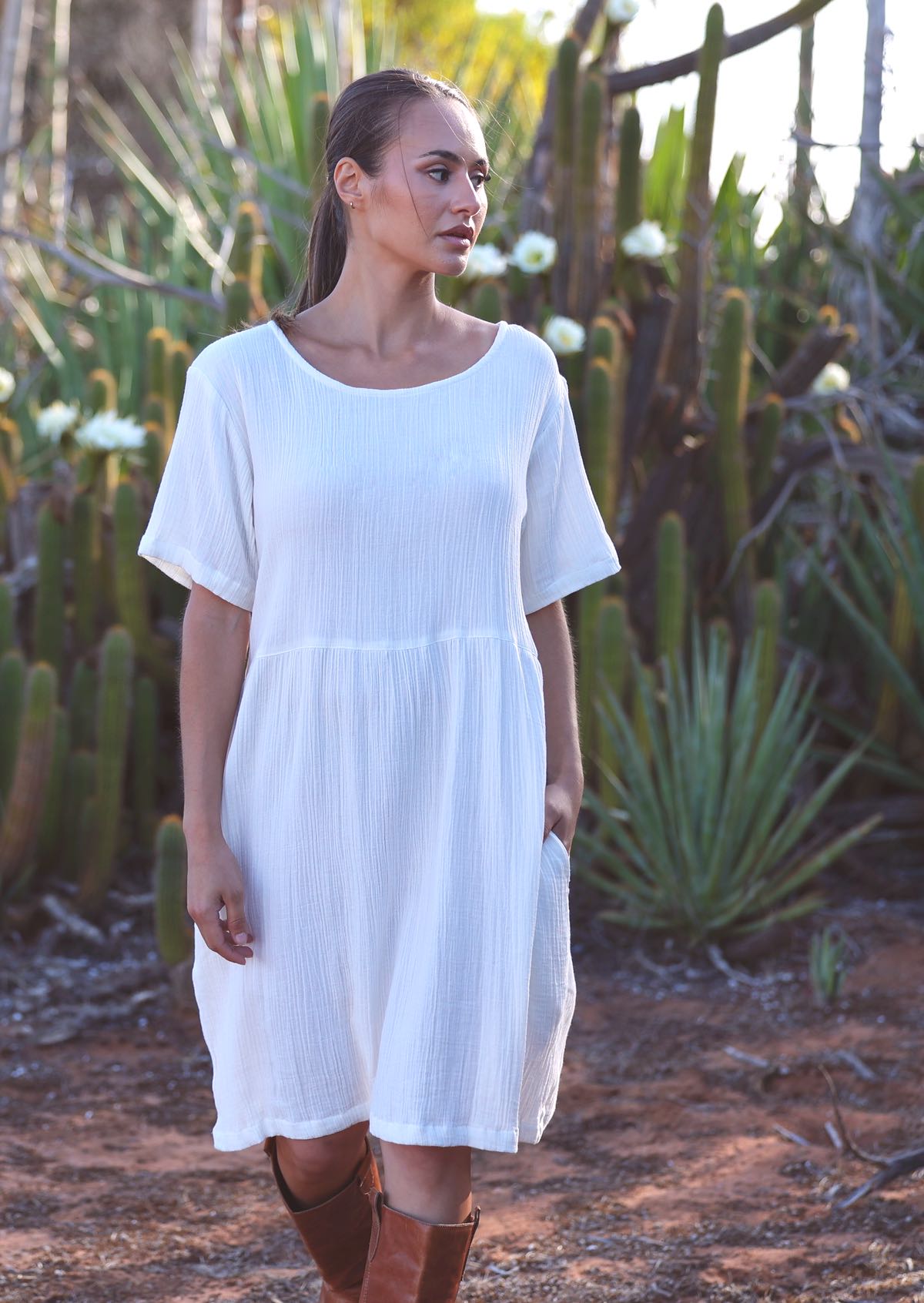 Woman with dark hair wearing white pure
cotton short sleeve sundress in front of cacti