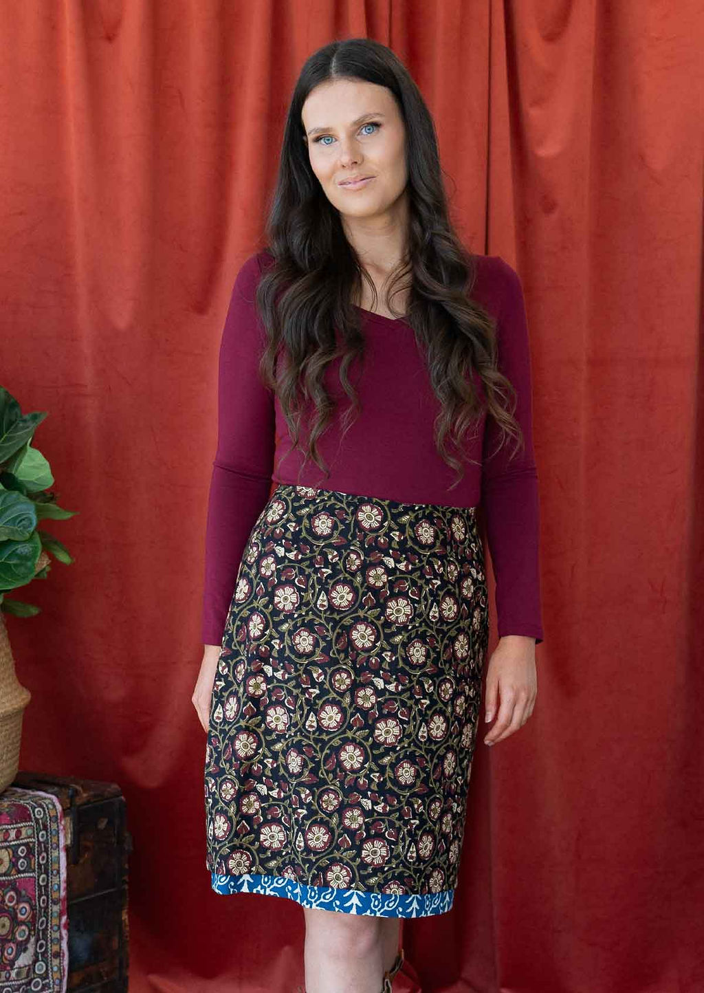 Model wears a reversible cotton skirt in maroon and cream florals on black base and a blue band popping out at the base.