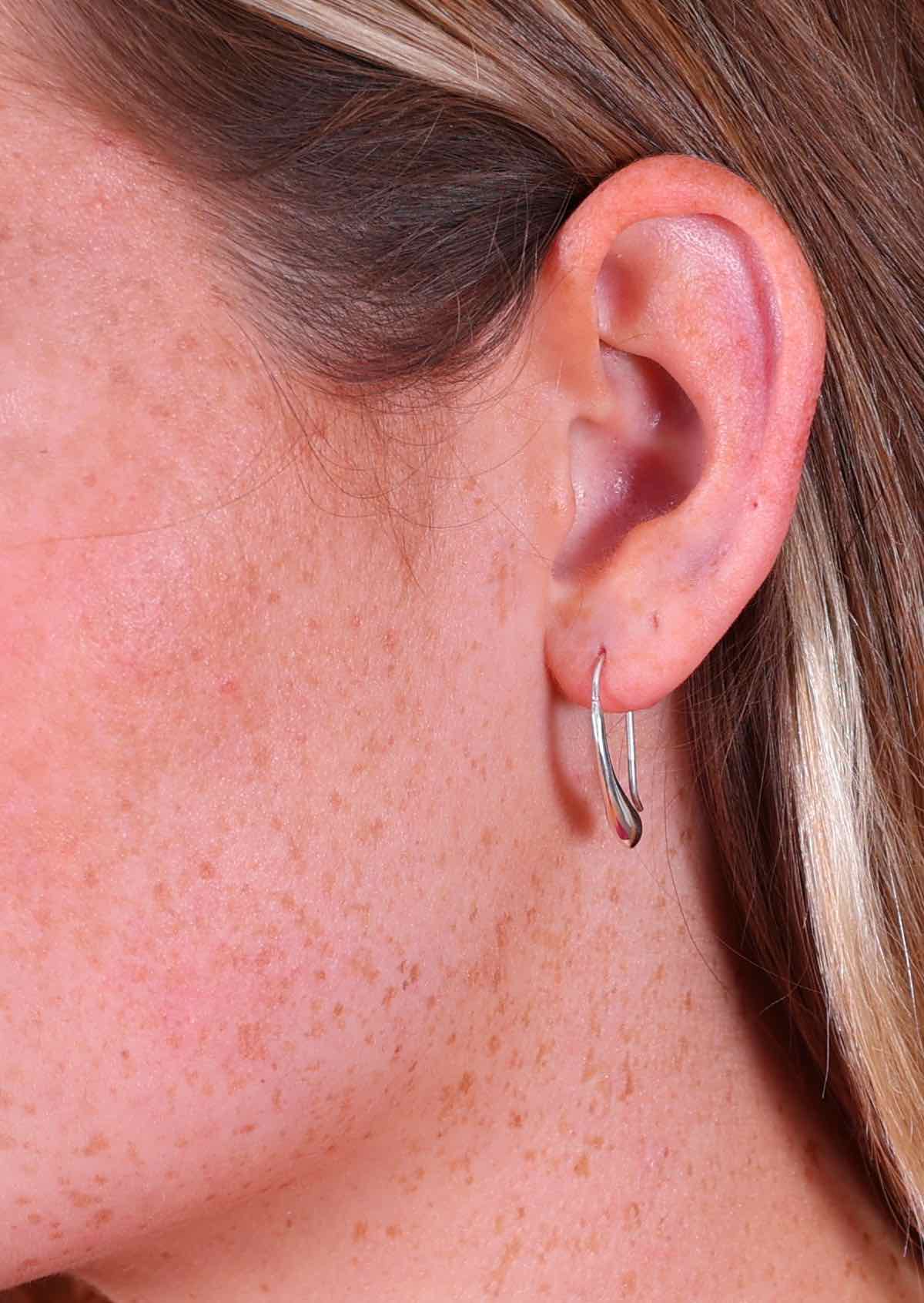 woman's ear wearing silver drop earring