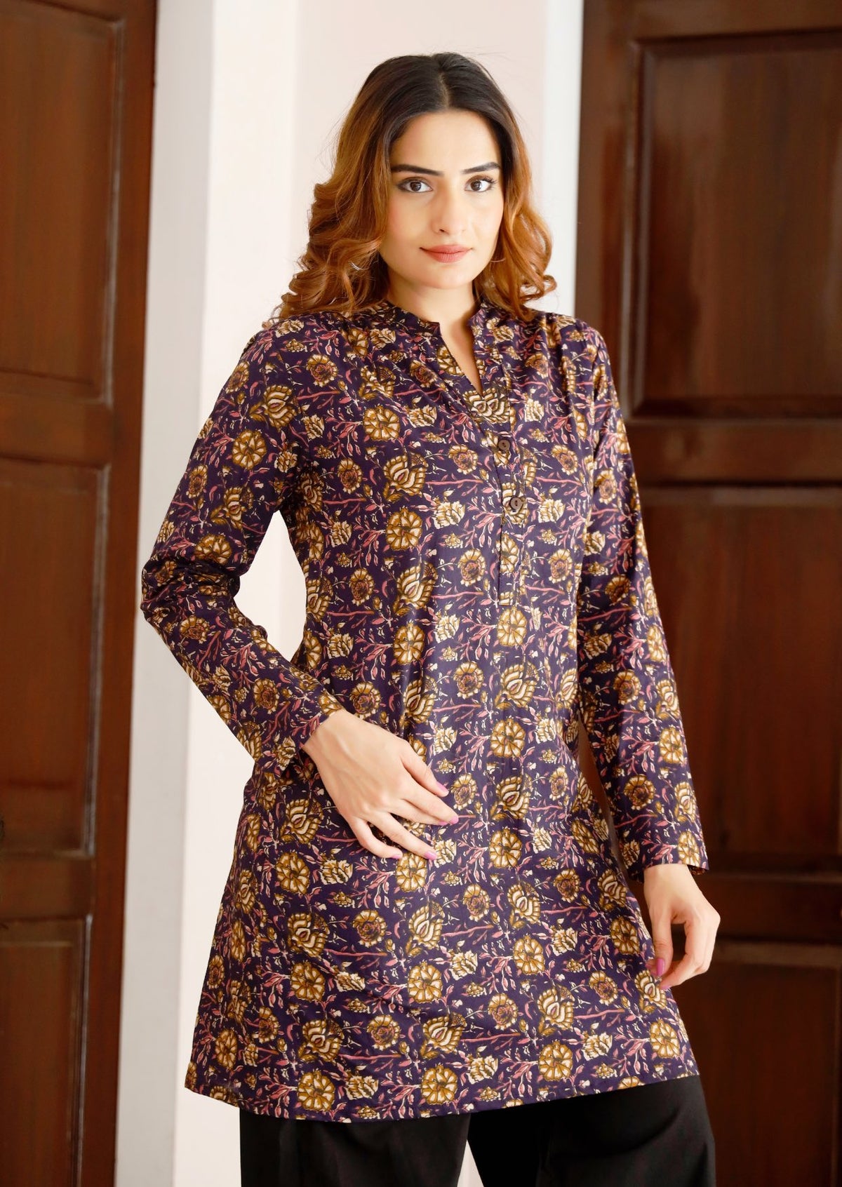 Woman wears lightweight, long cotton tunic with full sleeves in dark purple based floral print.