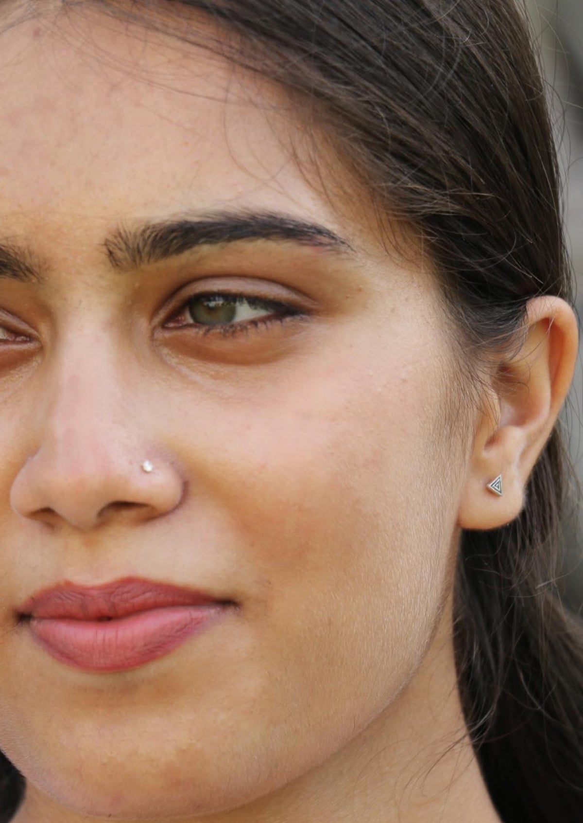 Woman with green eyes wearing small sterling silver triple ripple studs with triangular shape