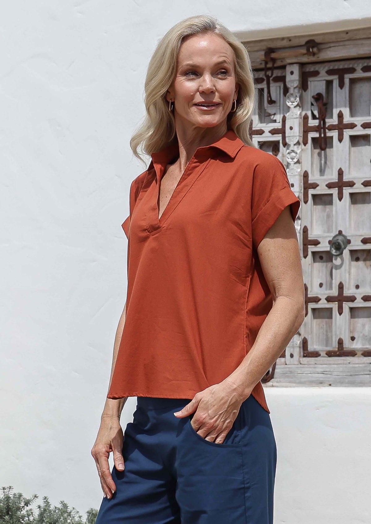 Woman wearing relaxed fit 100% cotton top with structured collar, folded cuff sleeves and V neckline