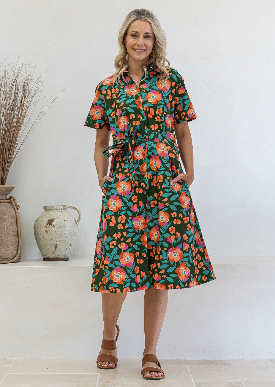 Model poses wearing a shirt style button through cotton dress with collar and a removable waist tie.