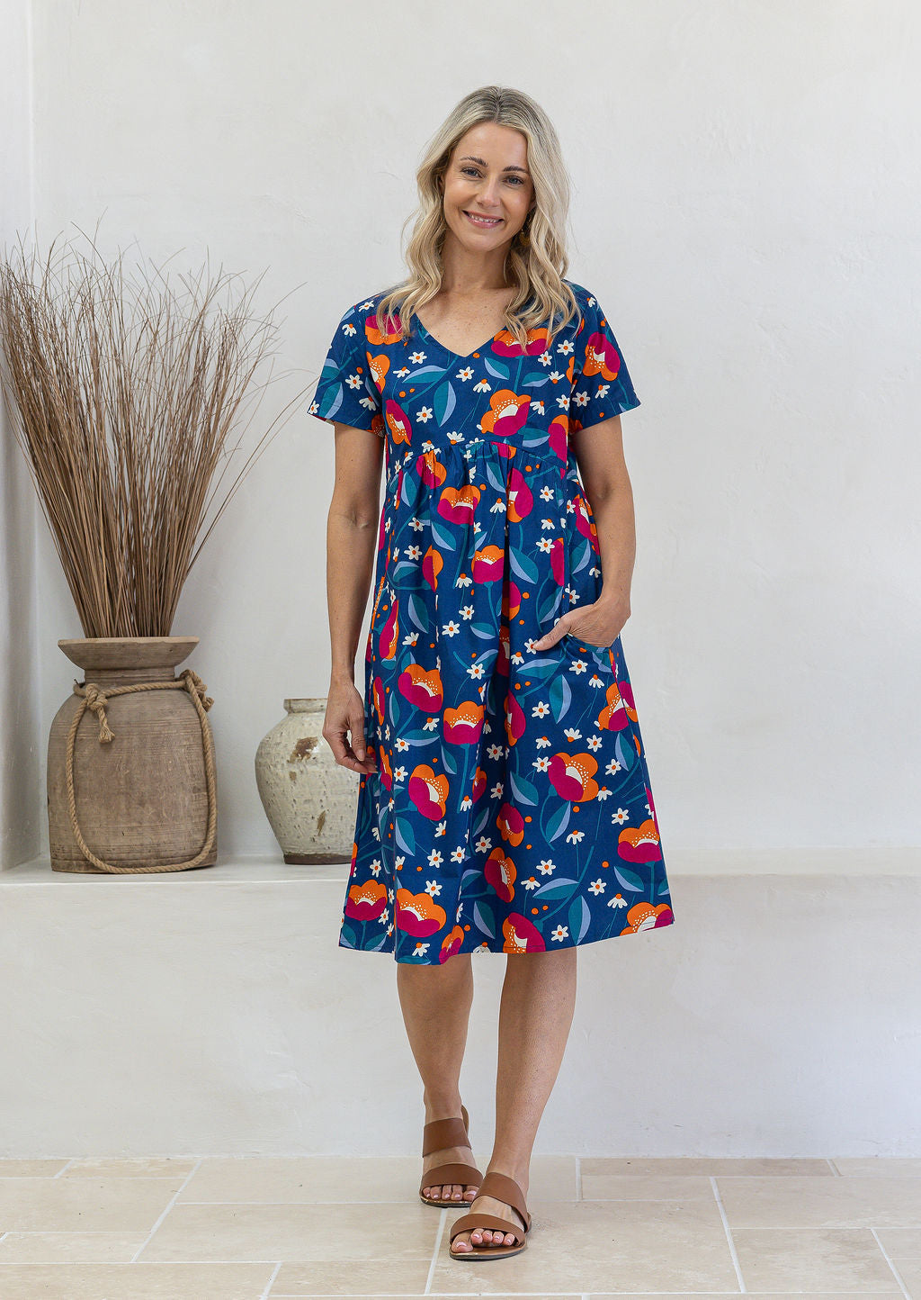 Model wearing a cotton V-neck short sleeve dress with empire waistline and pocket.