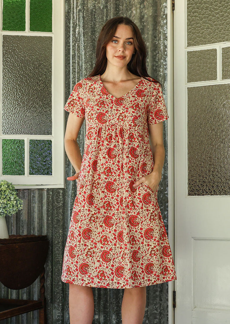 Model wearing a cotton V-neck short sleeve dress with empire waistline and pocket.