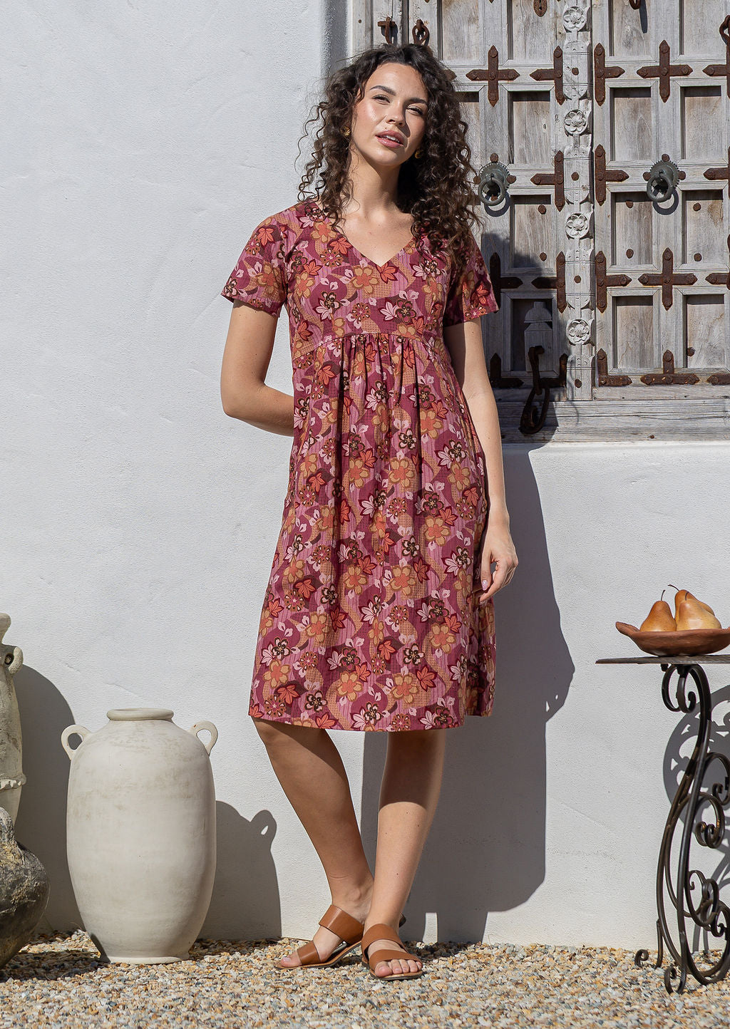 Model wearing a cotton V-neck short sleeve dress with empire waistline and hand in pocket.