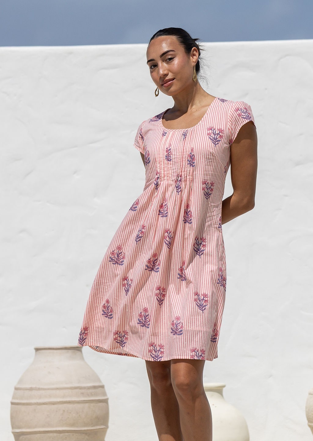 Woman wearing a 100% cotton Pink striped floral print cap-sleeve dress with smocked waist.