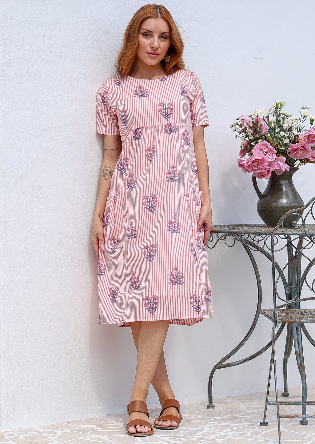 Woman wearing a 100% cotton Pink striped midi dress with floral print, short sleeves.