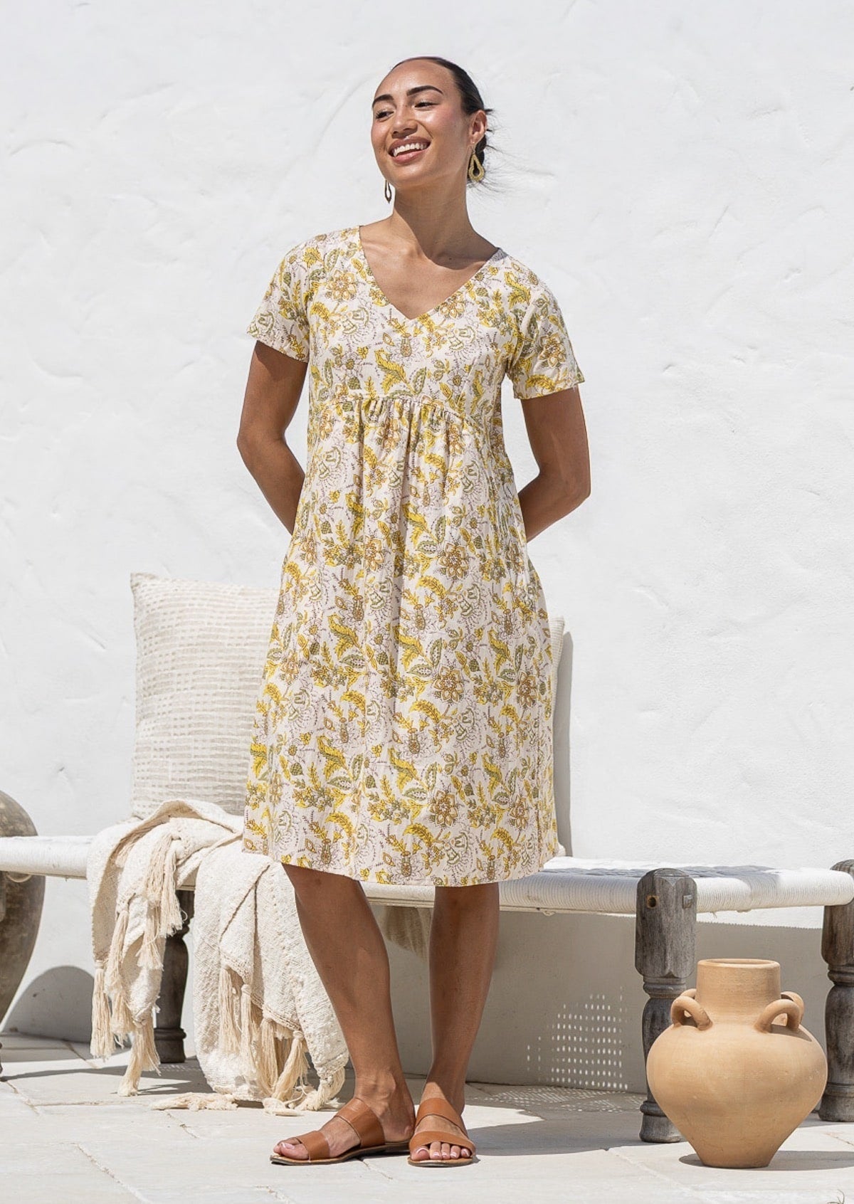 Woman wearing a 100% cotton Etta Dress in Primrose, yellow floral print, V-neck short-sleeve midi dress.