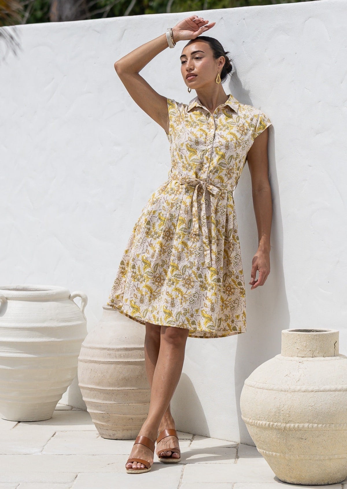 Woman wearing a 100% cotton cream based floral print Ursula Dress with cap sleeves and collar.