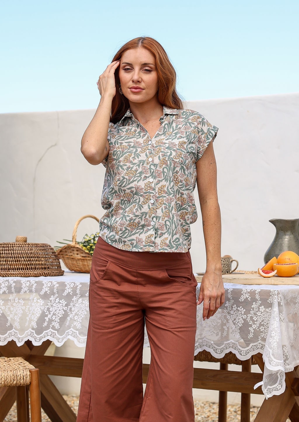 Woman poses in a slim fit button up shirt with shell buttons, structured collar and folded cuff sleeves