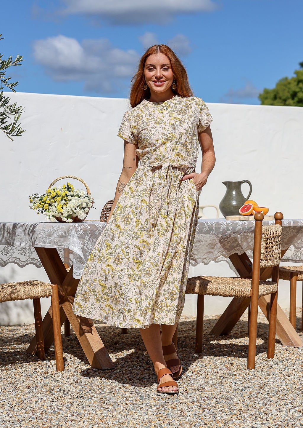 Woman wearing a cotton 1950's style short sleeved, button through cotton dress and high round neckline with one hand in pocket