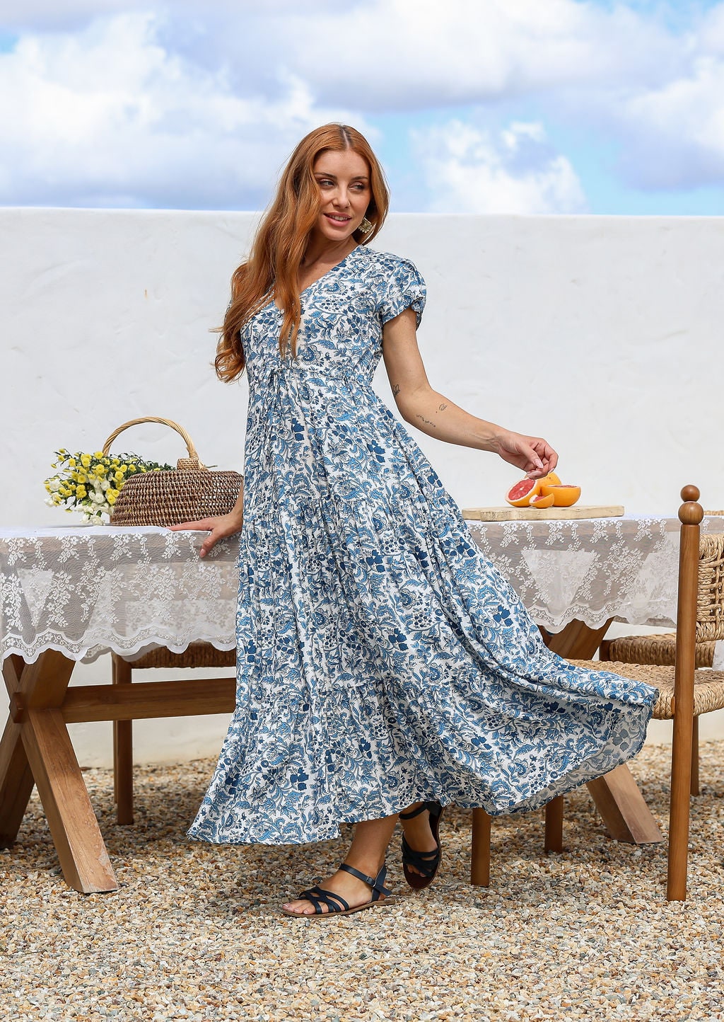 Blue and white floral print maxi dress with V-neck and short sleeves, on model, outdoor setting