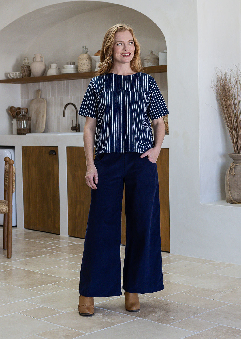 Woman wearing a navy blue and white striped short sleeved cotton top and navy pants.