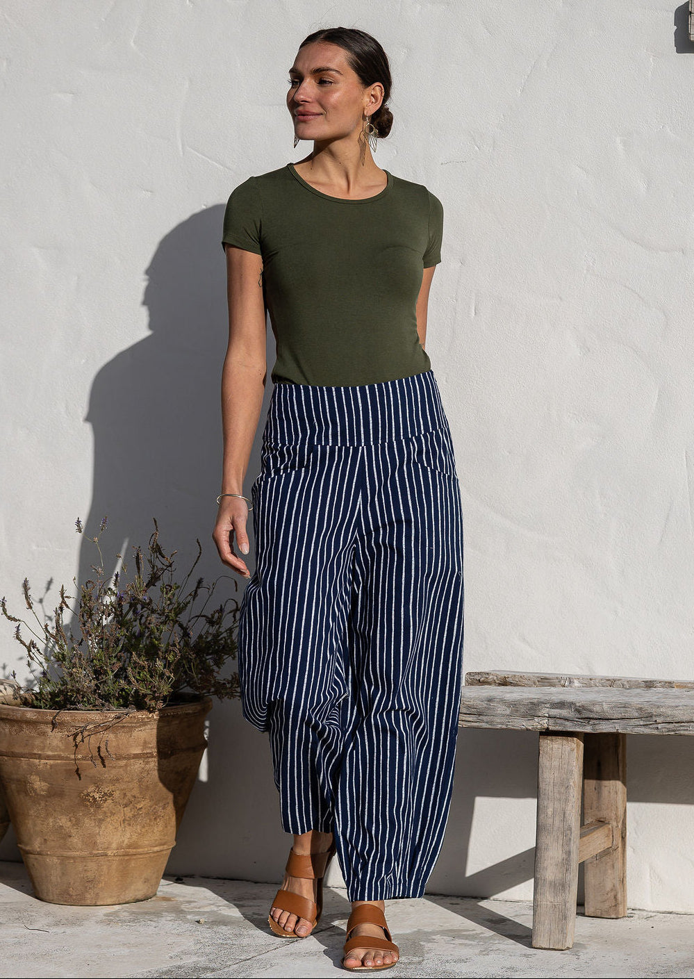 Woman wearing cotton wide leg pants in navy based white striped print with pockets paired with basic top