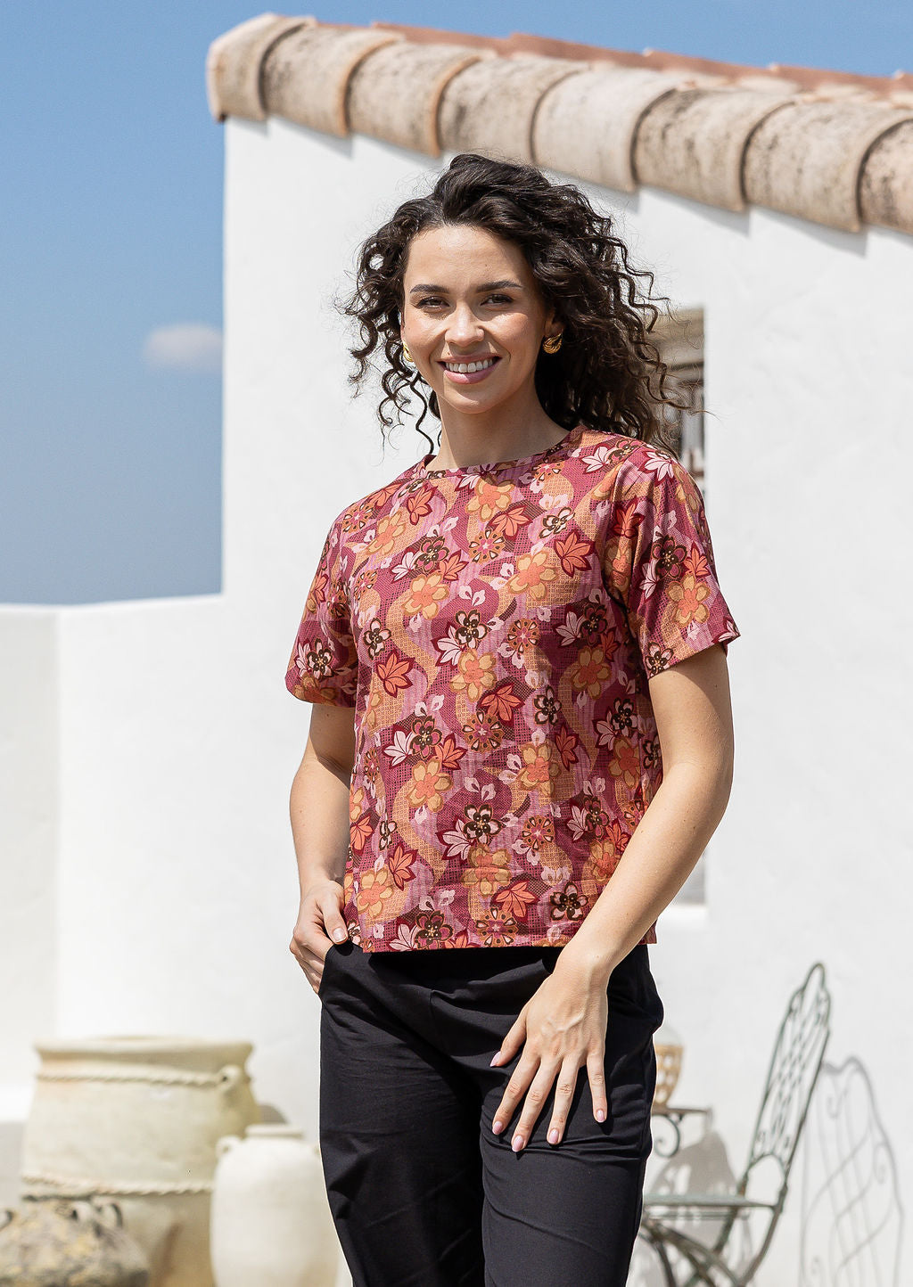 Woman wearing a loose fitting floral cotton top with short sleeves and high round neckline