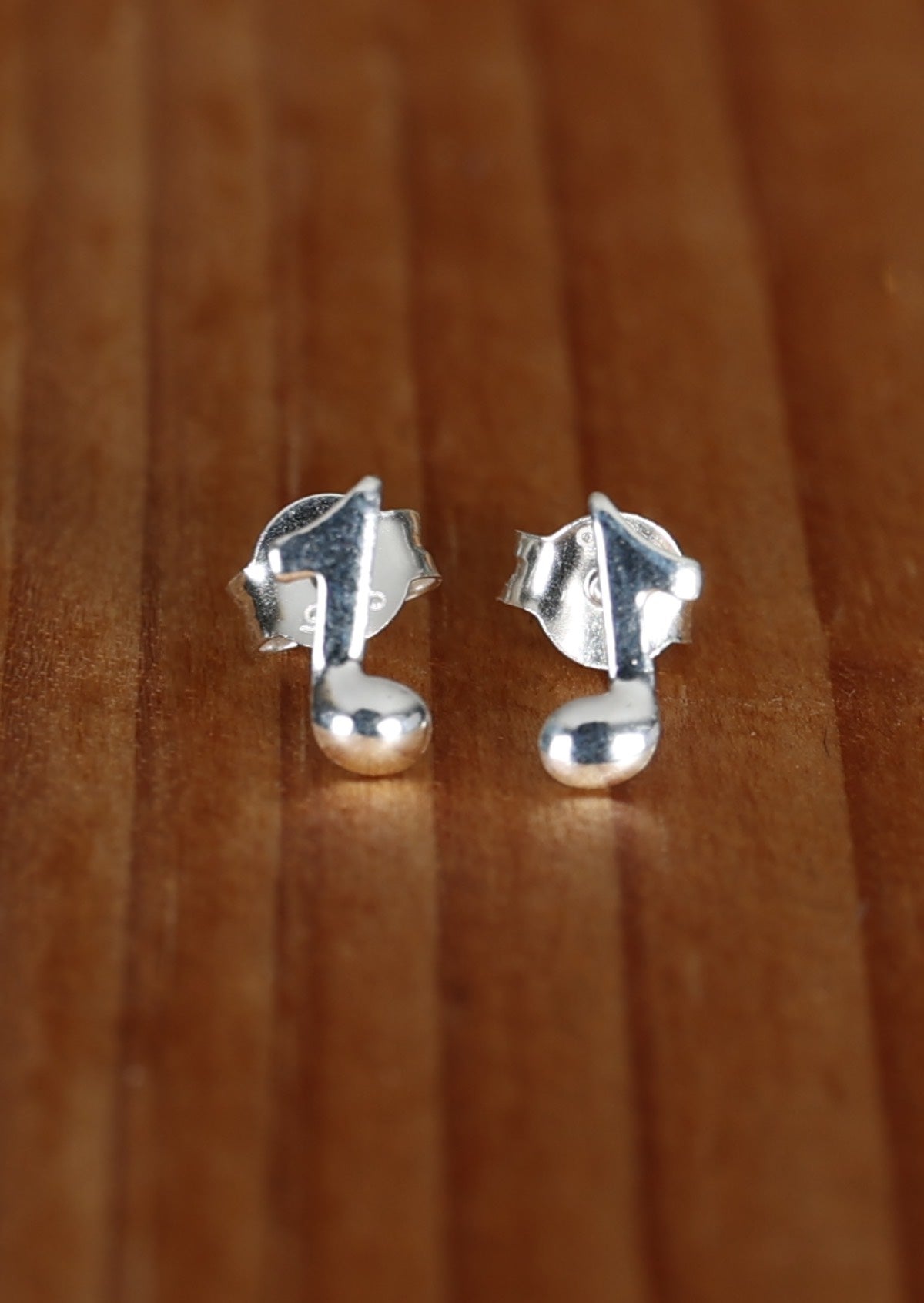 Eighth Note Quaver silver earring studs displayed on a wooden surface