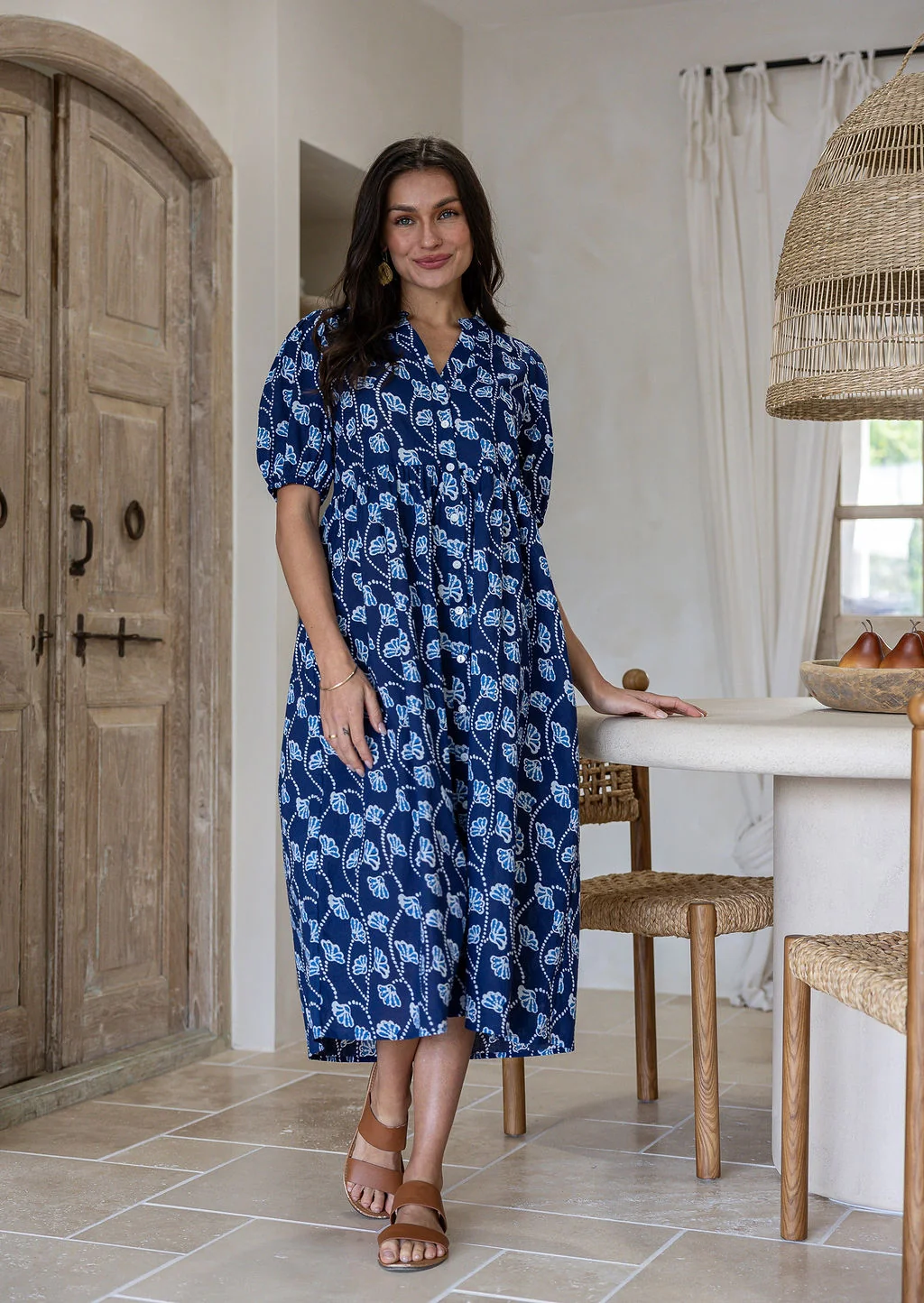 Woman wearing navy based colourful floral cotton button through dress with side pockets
