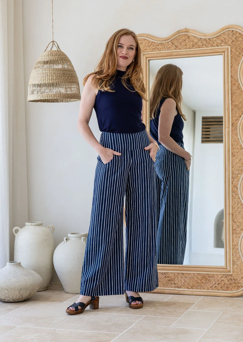 Model wearing a wide leg 100% cotton pant with navy based white striped print standing against a mirror
