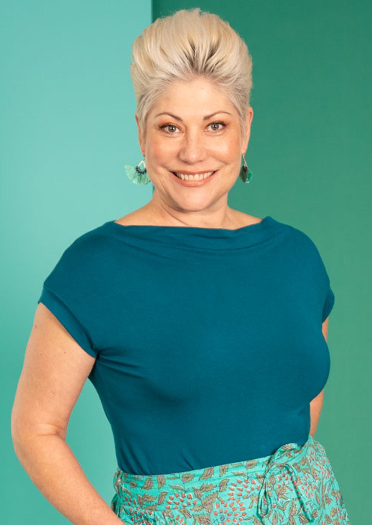 Woman wearing a wide neck mod teal stretch rayon boat neck top with floral pants.