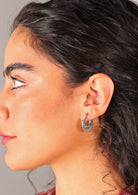 Woman wears silver 20mm diameter fine detailed earring with hinged clasp