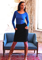 woman wearing black cotton corduroy skirt with blue long sleeve top hands in pockets
