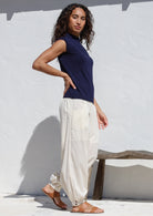 Woman poses in wide leg, pull-on cotton pants in white with pockets, cuffed ankles and shirred elastic at back waist.