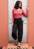 Woman wearing Acapulco Pants shirring across the back, front wide flat waist band wide leg cuffed at ankle with button closure pockets 100% cotton black