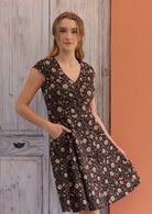 Model holding the cotton dress featuring cap sleeves, generous A-line skirt and a hand in pocket.