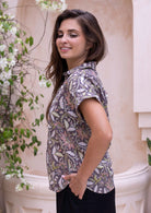Side pose of model wearing short sleeve relaxed fit cotton top with V-neckline, collar and folded cuff sleeves.