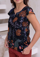 Model wearing a cotton, tailored hip length top with cap sleeves and round neckline with keyhole cutout.