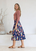 Woman wearing floral print navy blue midlength skirt with side zipper and belt loops.