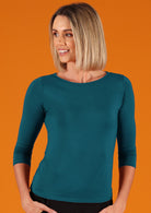 Woman wearing a rayon boat neck teal 3/4 sleeve top.