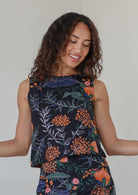 Woman wearing a relaxed fit sleeveless floral top against a plain background