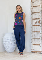 Woman wearing a sleeveless cotton top with colourful polka dots and navy base, paired with navy harem pants