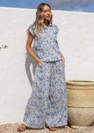 Woman wearing a blue floral print cotton shirt which is 100% cotton against a white background.