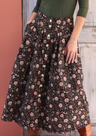 black based cotton button through skirt with box pleats and belt loops, with hand in pocket