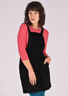 woman wearing black corduroy pinafore over pink top
