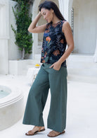 Model posing in a sleeveless floral cotton top with a round neckline, paired with green cotton pants, hand in pocket